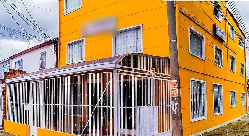 Fachada naranja de la sede Quinta Mutis, de tres pisos y con reja blanca