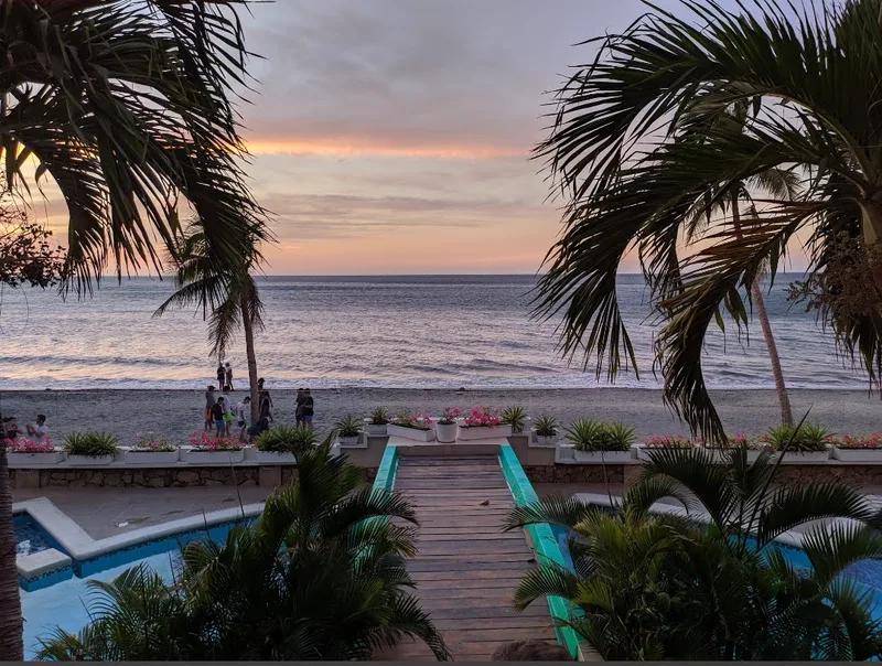 Atardecer desde el edificio: la pasarela entre las piscinas lleva directo a la playa
